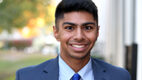 Young man smiling wearing a blue suit and tie