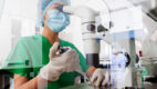 An Asian woman pipes samples onto a slide to examine under a microscope