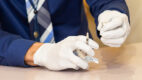 Hands wearing rubber gloves holding syringe to illustrate why Capital Region and U.S. hospitals require staff Covid vaccination