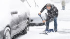 Man shoveling snow next to a car