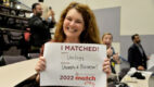 An Albany Medical College resident holds up a sign denoting where she matched for her residency, Urology at the Univesity of Wisconsin