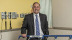 Jason Mouzakes, MD, ’95, standing in a patient room