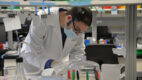 Jeremy Logue, PhD, bent over a desk in a lab taking notes