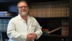 Dr. R. Clement Darling III standing in front of a book shelf