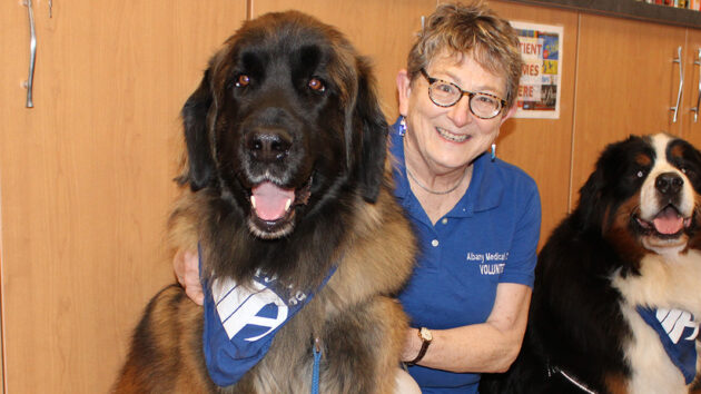 Volunteer Happy Scherer with therapy dogs, Chewy (Chewbacca), and Bruno Mars