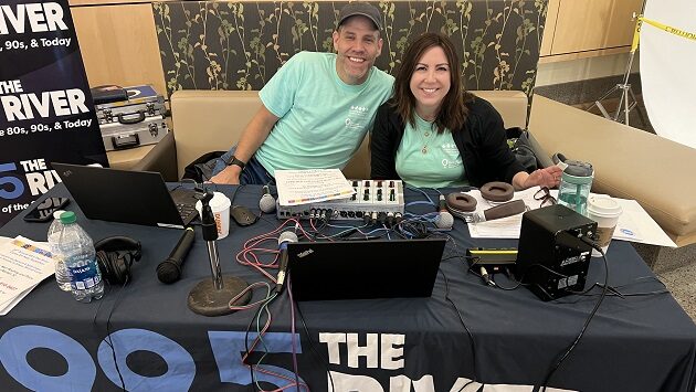 two radio hosts sitting at a table with microphones