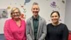 three people standing in a doctor's office. It's the high risk infant follow up team