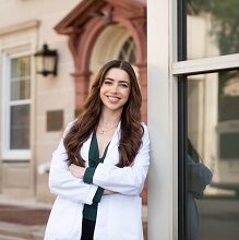 Medical student leans up against a building