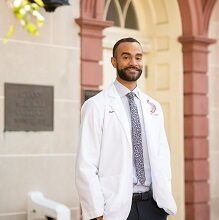 medical student in white coat outside of the college