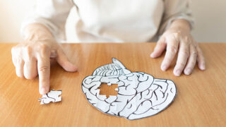 Elderly woman hands putting missing jigsaw piece together.