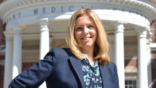 Michele Kakely Skumurski, Senior Vice President of Finance, standing in front of Albany Medical Center's pillars entrance.