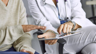 Female clinician reviewing data on a tablet screen with a female patient.