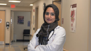 Rheumatologist Arifa Javed, MD standing in a clinic hallway