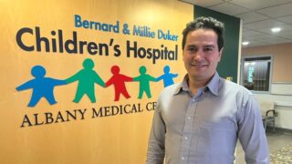 Dr. Ahmed Deniwar standing in front of the children's hospital sign