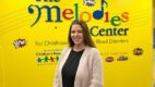 Dr. Harney standing in front of the Melodies Center yellow wall