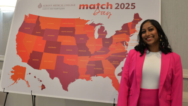 A medical student stands in front of a map of the U.S. on Match Day 2025