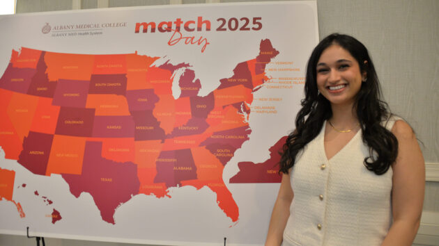 A medical student stands in front of a map of the U.S. on Match Day 2025