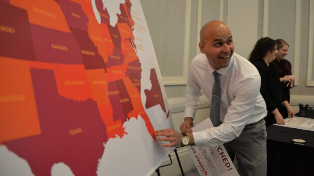 A medical student points to a map of the U.S. to show where he matched at Albany Medical College's Match Day 2025